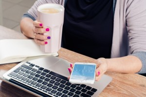 Woman working, laptop, phone, coffee.